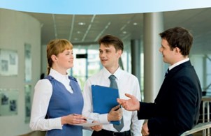 An image showing a female and 2 males chatting in a professional environment