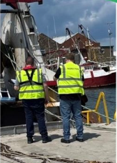 An image of 2 male inspectors looking at a fishing vessell